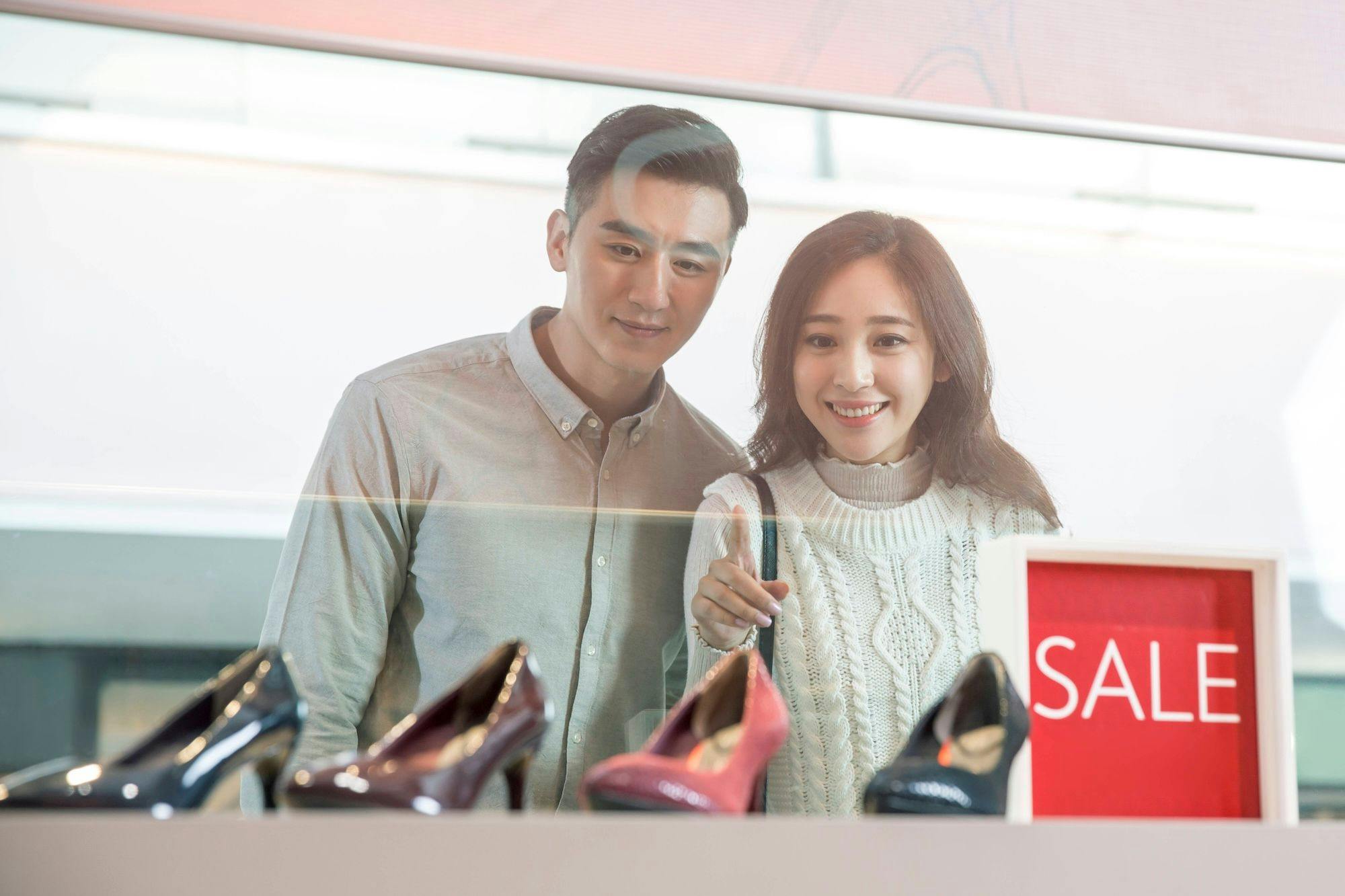 China Wirtschaft, Konsum, Shopping, Konsumverhalten: Chinesisches Paar beim Window Shopping bleibt neben einem SALE Schild stehen