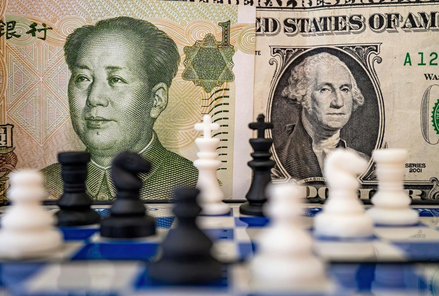 China Aktien, Aktienmarkt, Stocks, Kapitalmarkt, Finanzen: Nahaufnahme eines Schachbretts, auf dem ein US-Dollar und ein chinesischer Yuan liegen