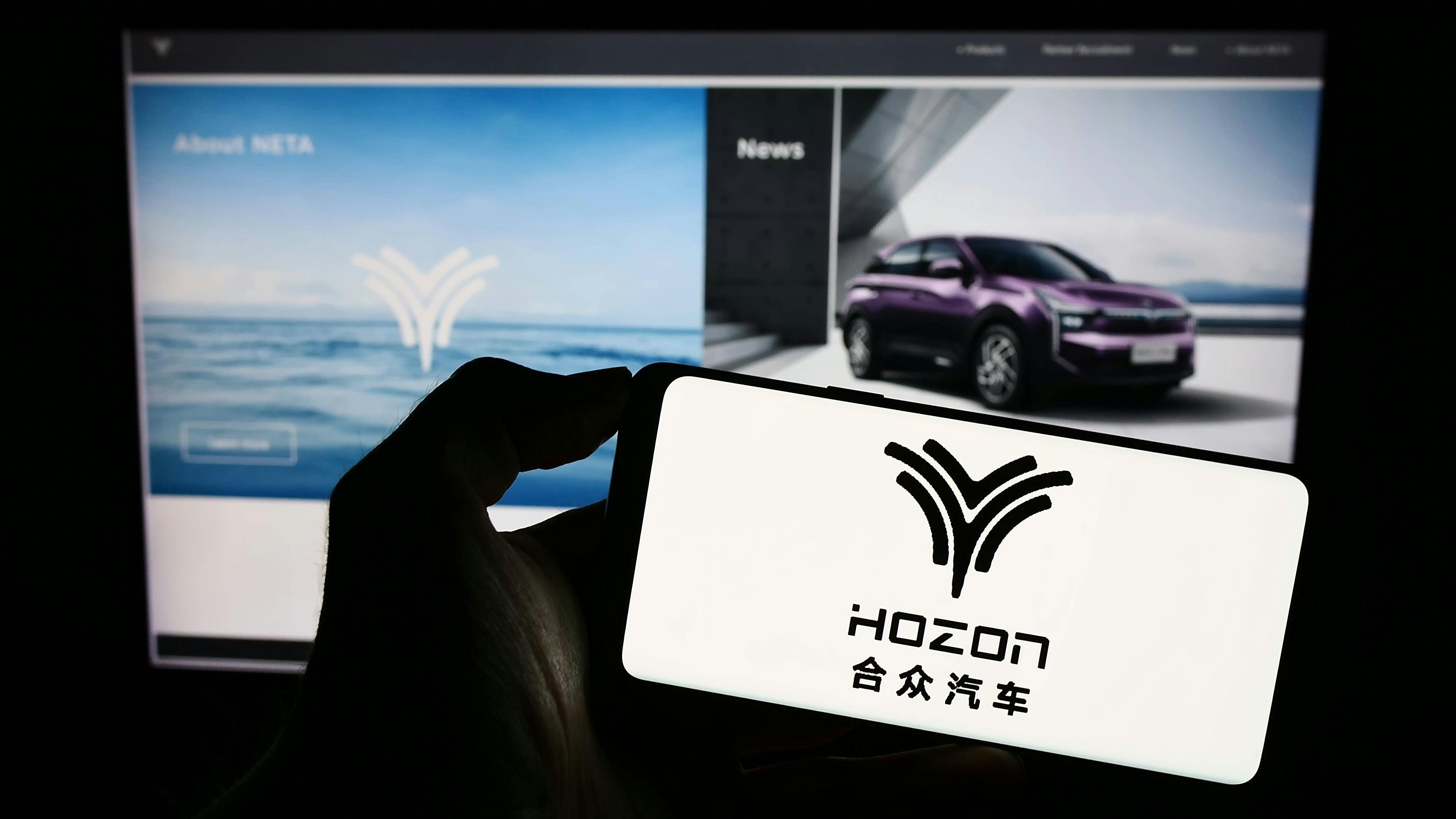 China Mobilität, Autos, Automarken, Automarkt: Eine Person hält ein Mobiltelefon mit dem Logo von Hozon Auto New Energy Automobile Co. Ltd. auf dem Bildschirm