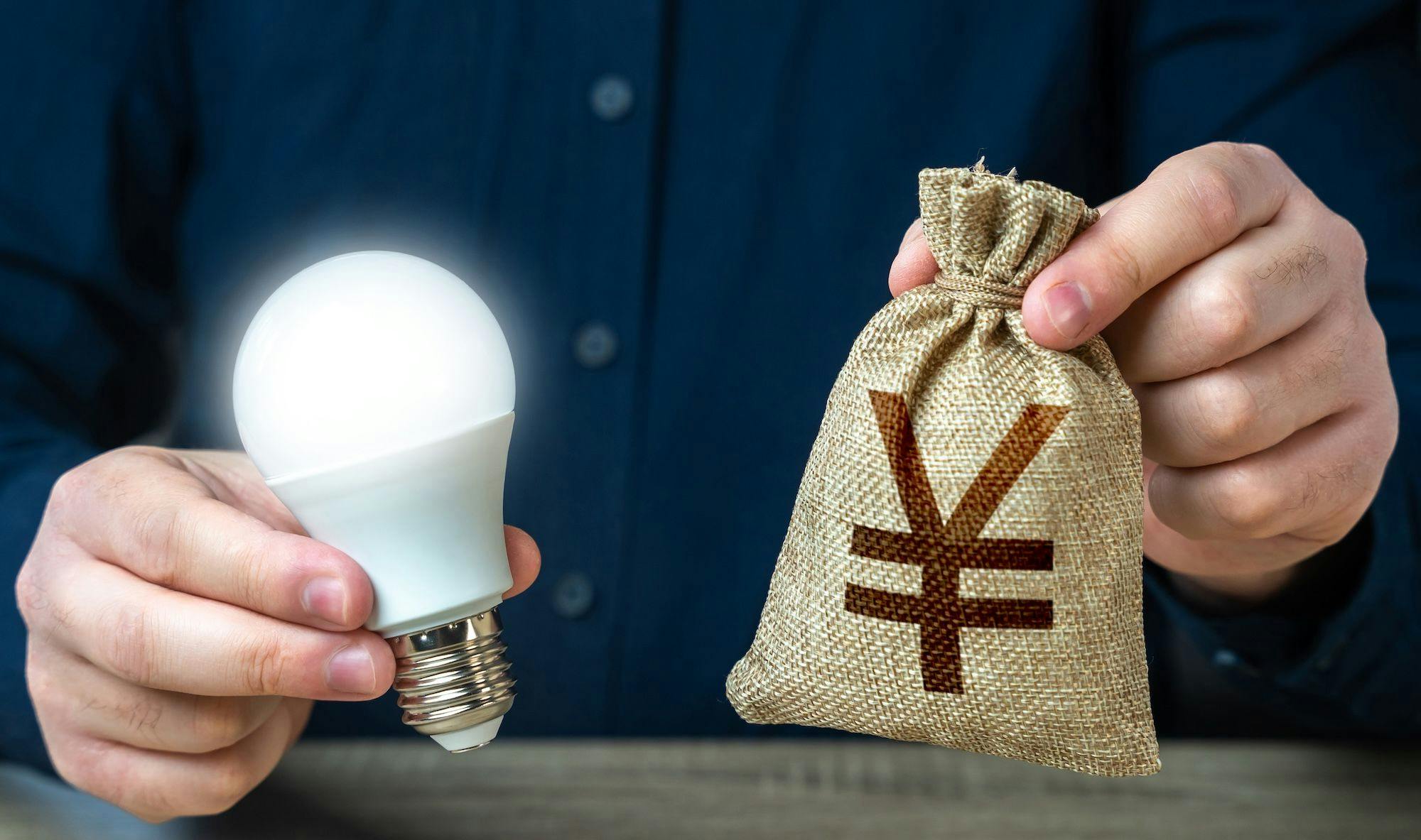 China Wirtschaft, Industrie, Technologie, Patente: Das Foto zeigt einen Mann, der in einer Hand eine Glühbirne, in anderer einen Yuan-Sack hält