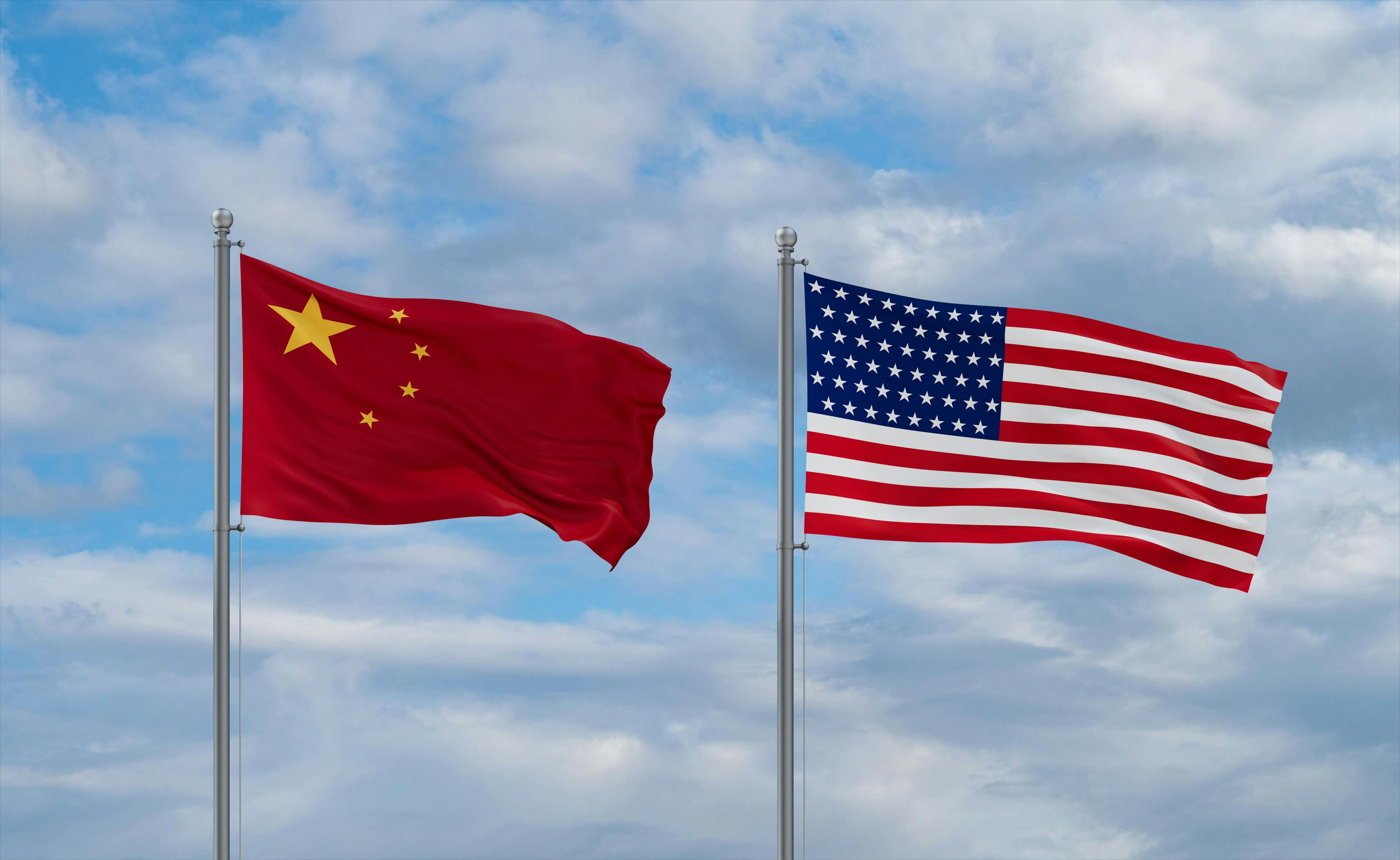 USA and China flags waving together in the wind on blue cloudy sky, two country relationship concept Model Released Property Released 