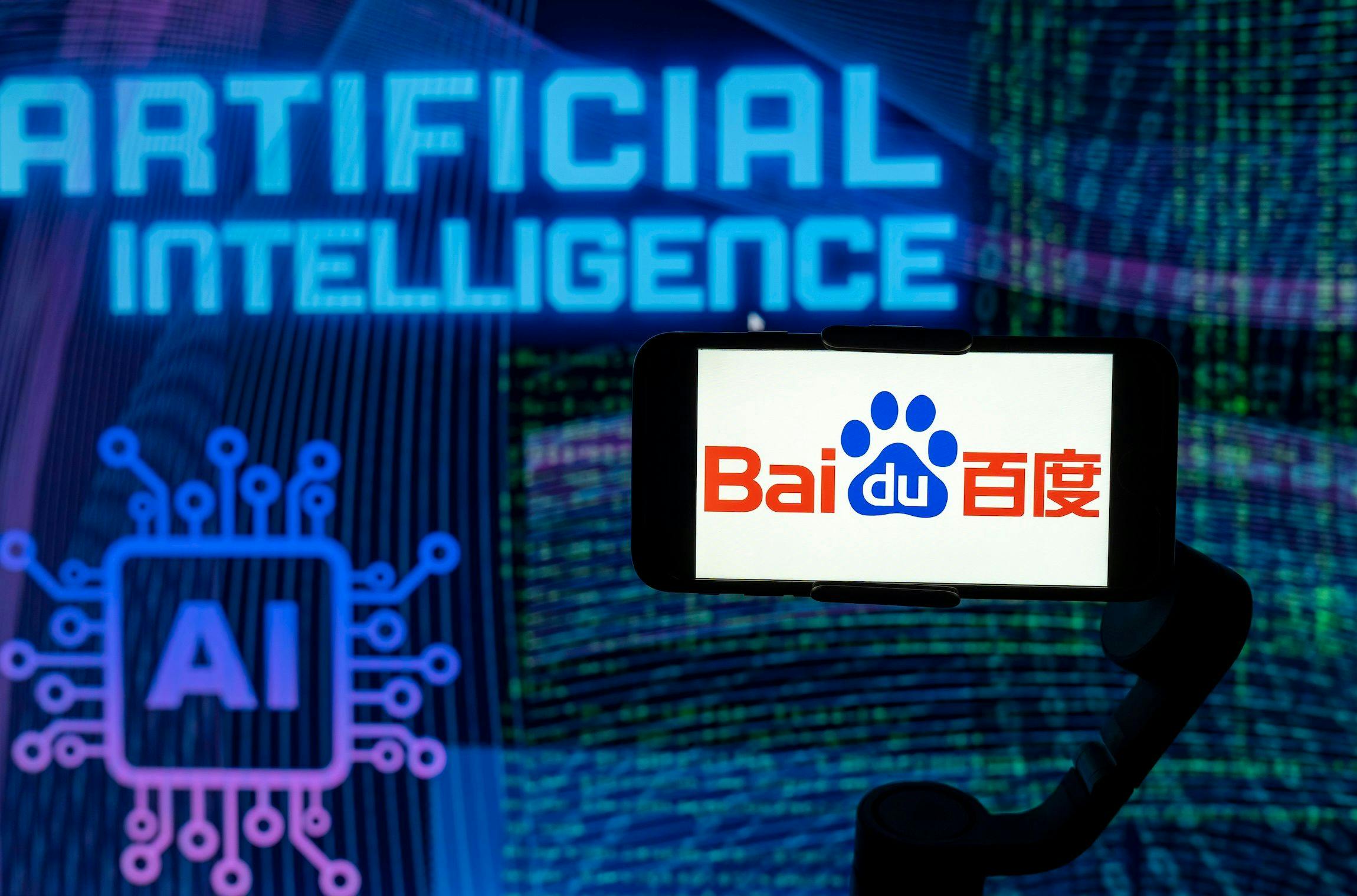 Auf diesem Foto ist das Logo von Baidu auf dem Bildschirm eines Mobiltelefons zu sehen, im Hintergrund steht AI (künstliche Intelligenz).