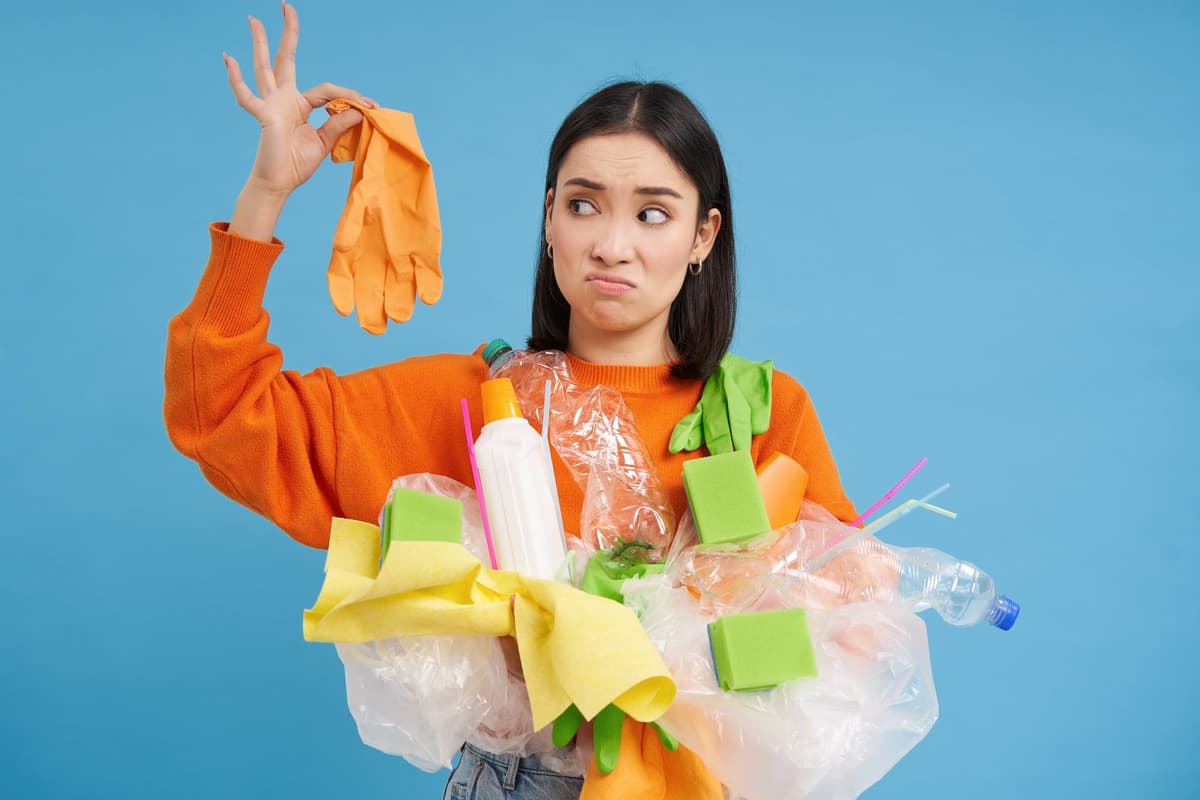 China Technologie, Wirtschaft, Industrie, Umwelt, Abfall, Recycling, Plastik: Junge Frau hält Plastikmüll in der Hand, schaut mit schockiertem Gesicht auf den Handschuh