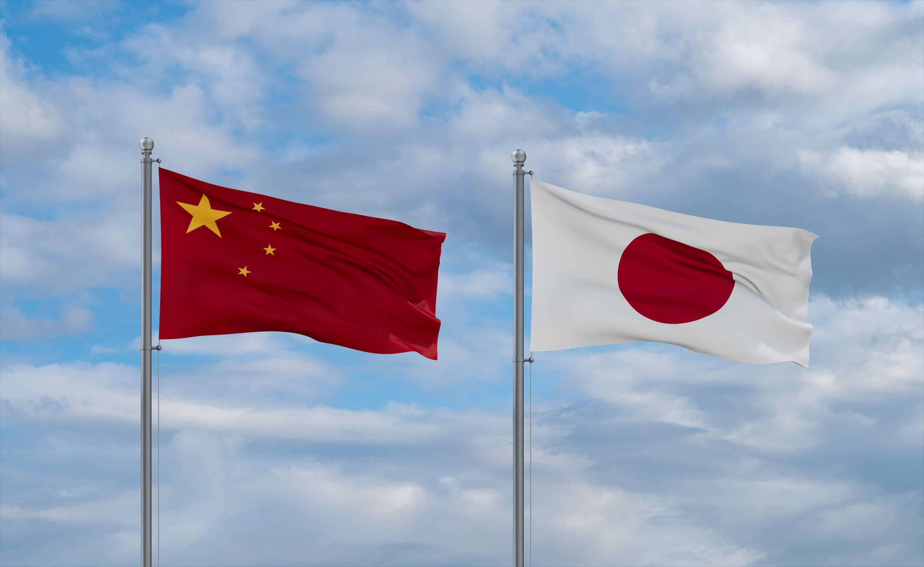 Chinesische und Japanische Flaggen wehen nebeneinander an Fahnenmasten