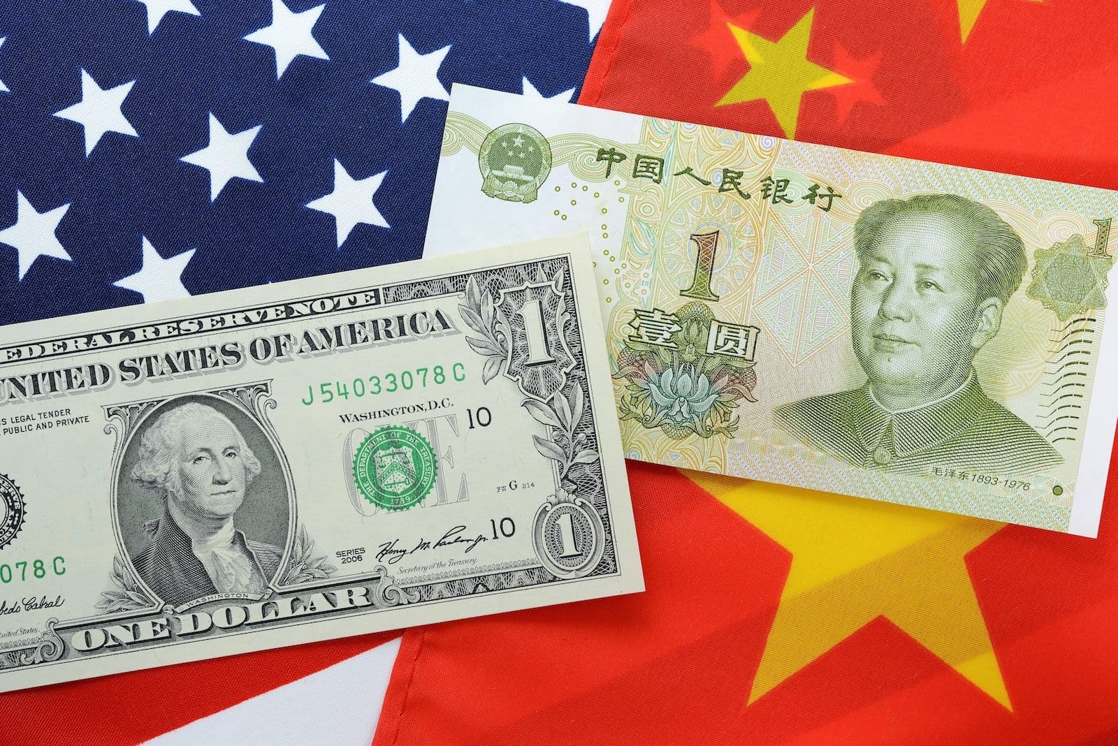 Das Foto zeigt die Flaggen der USA und China mit der jeweiligen Landeswährung darauf
