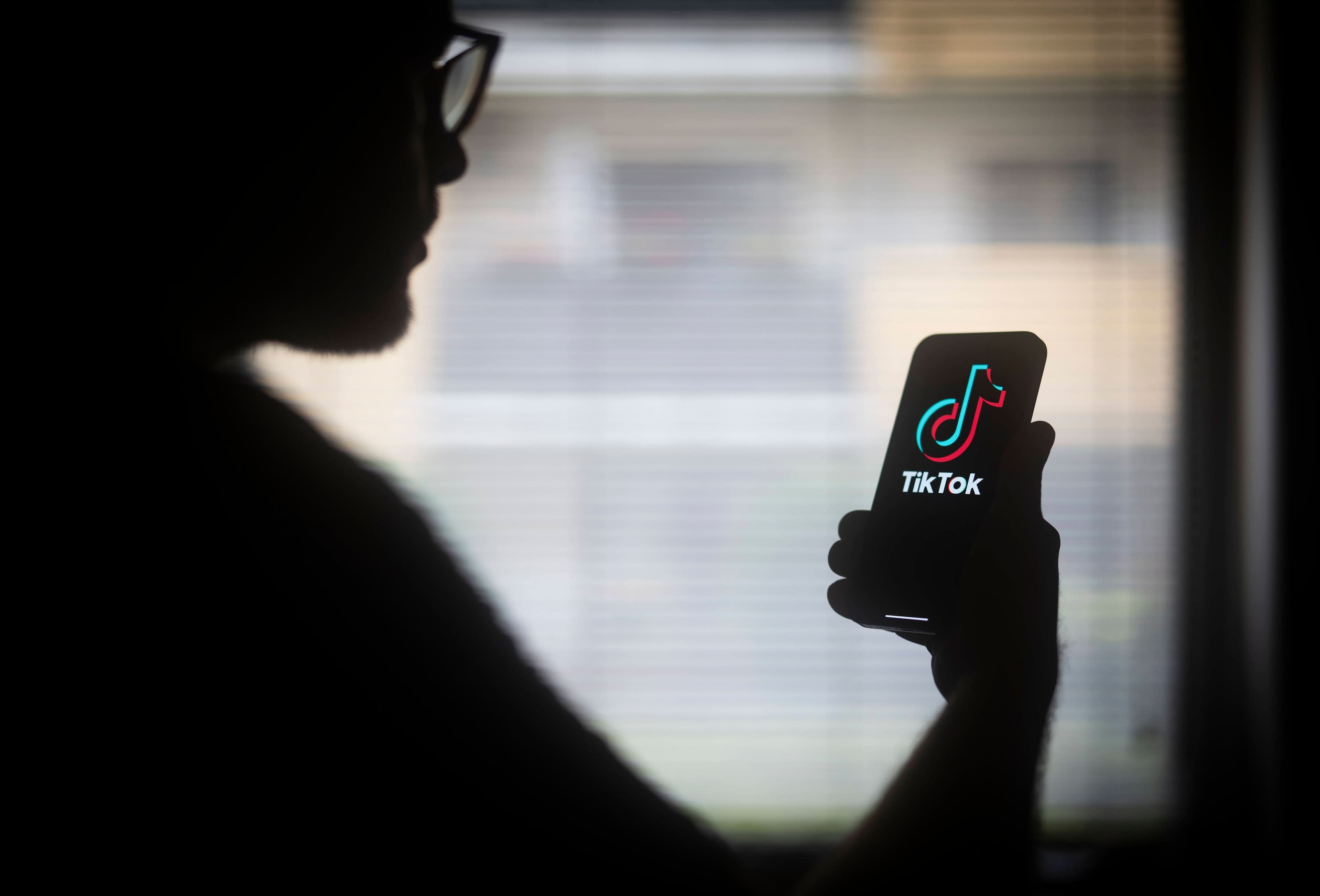 USA TikTok Bann: Das TikTok-Logo ist auf einem mobilen Gerät zu sehen, das ein Mann mit Brille in der Hand hält