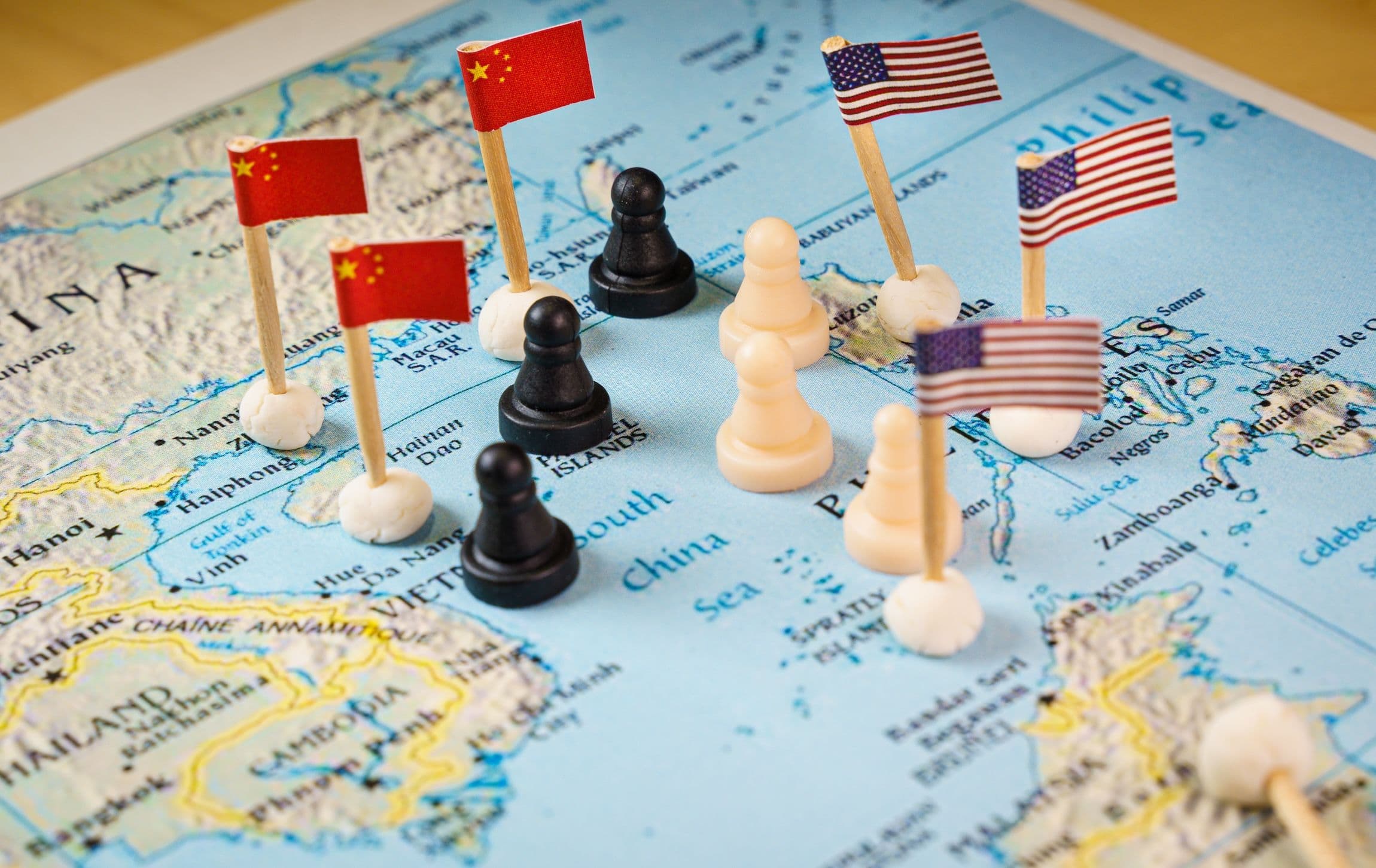 Chinesische und US-amerikanische Flaggen mit Schachfiguren, die den Konflikt und die Kontrolle über das Südchinesische Meer symbolisieren.