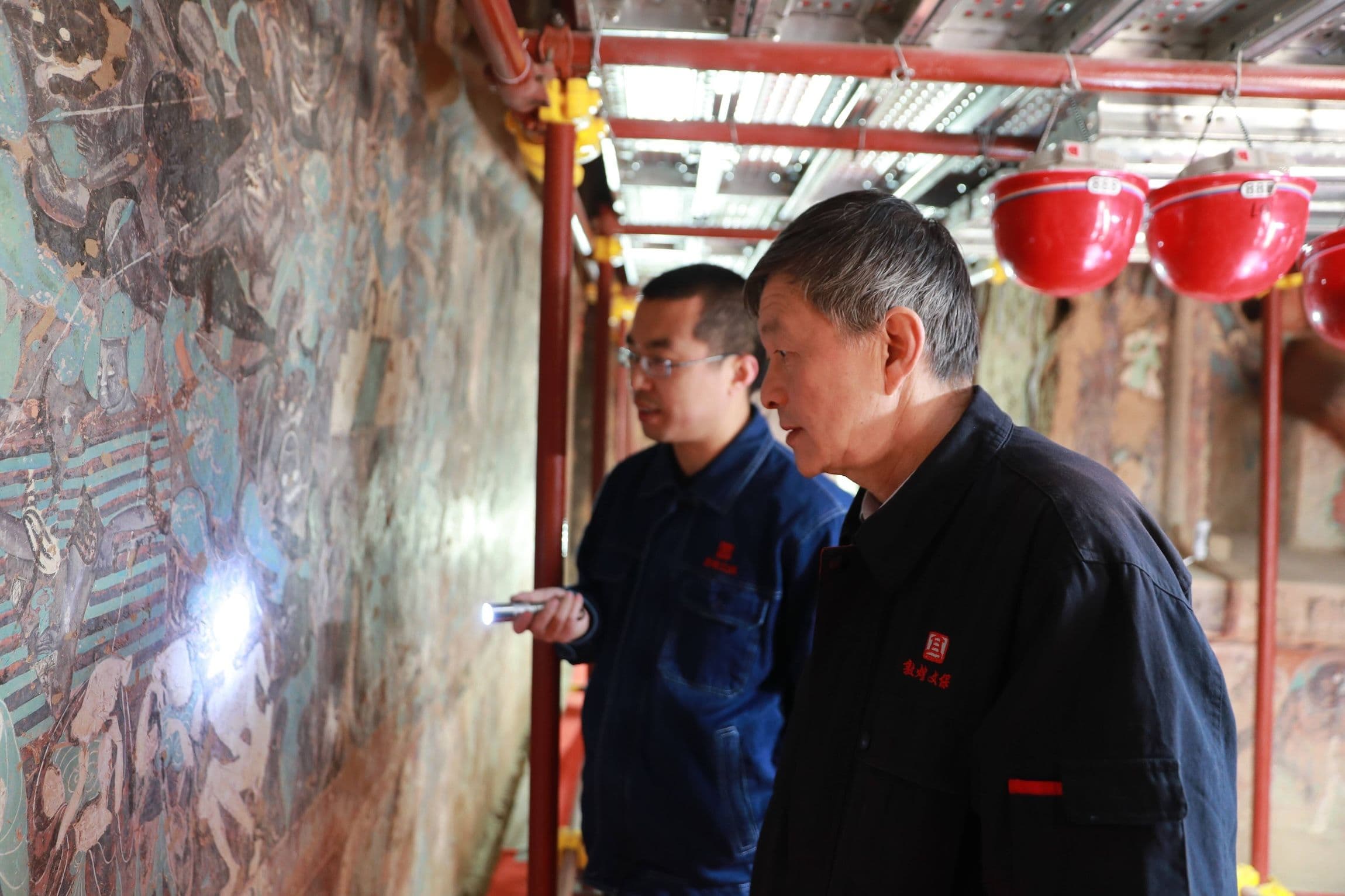 Su Bomin (R) überprüft die Restaurierung von Wandmalereien in den Mogao-Grotten in Dunhuang in der nordwestchinesischen Provinz Gansu
