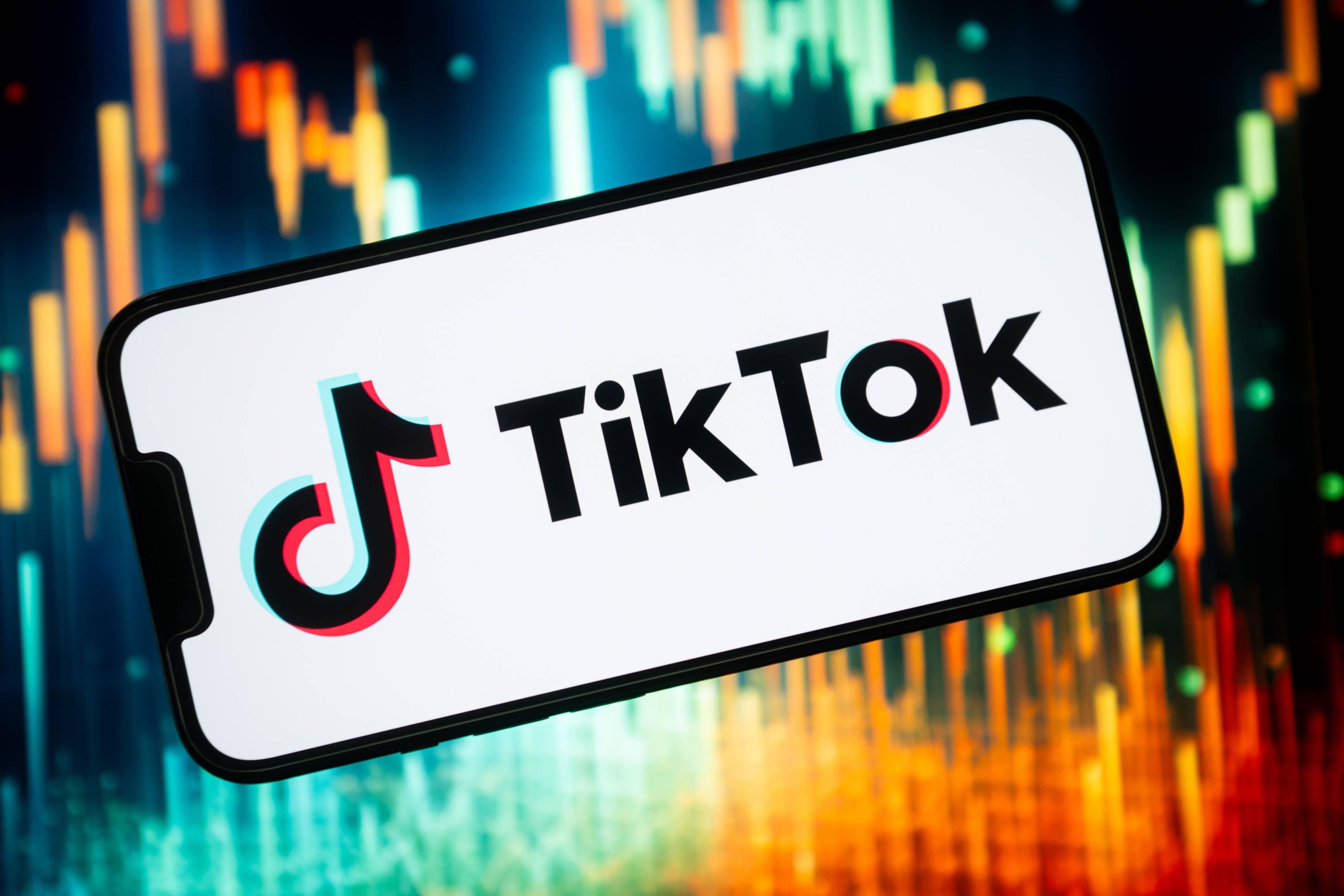 China Politik, China USA, USA TikTok: Foto zeigt Smartphone mit TikTok Logo vor buntem Hintergrund