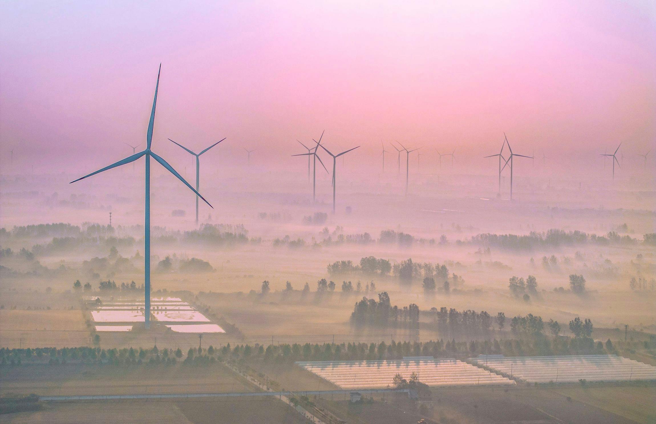 Windkraftanlagen, Dörfer und Bäume im Nebel in der Stadt Shangtang, Suqian City, Provinz Jiangsu, China