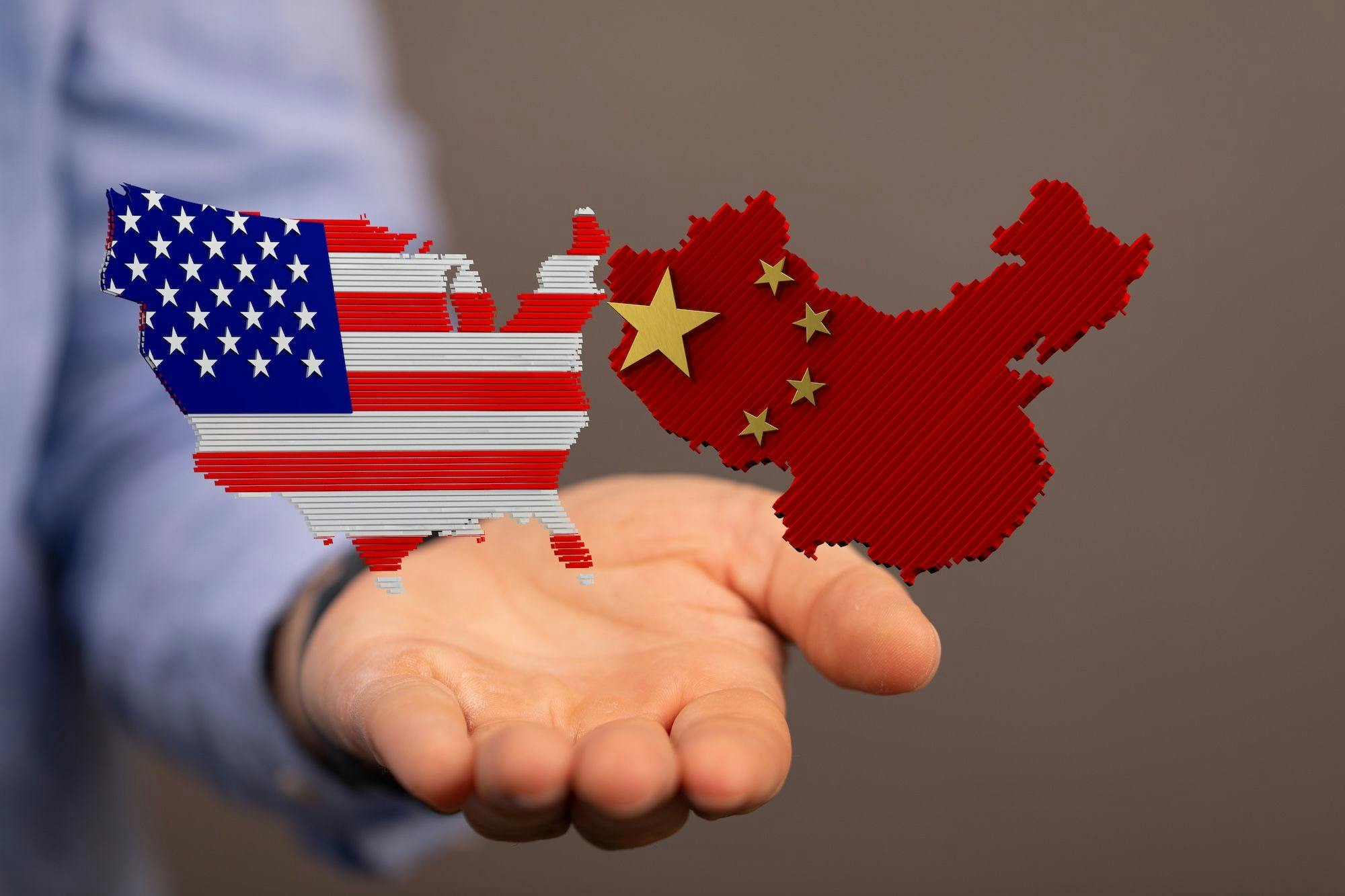 China USA Kooperation, Zusammenarbeit, Konflikt, Streit: Eine Hand hält die US-Amerikanische und chinesische Flagge, beide in der Form des jeweiligen Landes